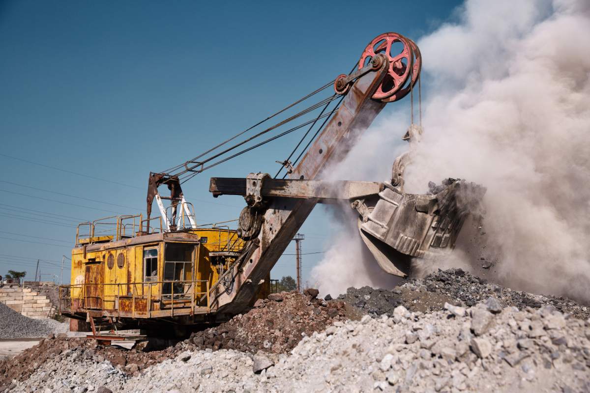 Huge quarry bucket excavator works in a hot outdoors slag dump. Heavy industrial metallurgical foggy landscape