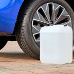 A white canister with a diesel exhaust fluid DEF for reduction of air pollution standing near a blue car